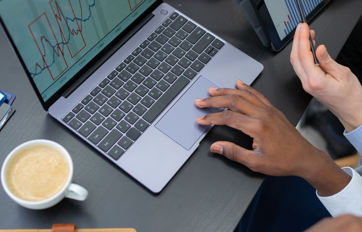Colleagues reviewing information on a laptop and tablet at a shared desk. Illustrative stock photograph.