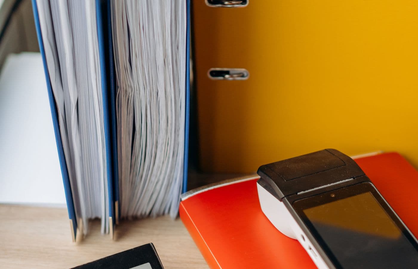 Documents, office files, and a payment terminal arranged on a desk. Illustrative stock photograph.