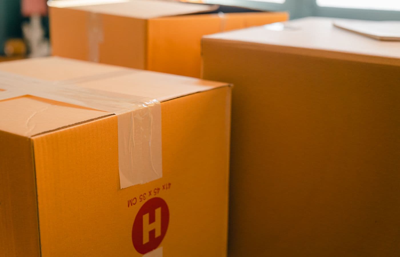 Packed cardboard moving boxes in a sunlit room. Illustrative stock photograph.