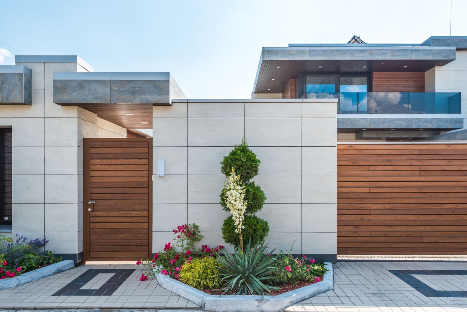 Contemporary home with a wood and concrete facade and a planted entrance garden. Illustrative stock photograph.
